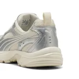 Championes Puma modelo Milenio Tech, color arena con detalles metalizados en tono plata. Presentan base de malla transpirable, suela robusta y el característico diseño de la franja Formstrip en el lateral.