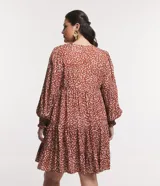 Vestido corto amplio color ladrillo con lunares irregulares color crema, cuello redondo con lazo, mangas largas con puños anchos y bajo fruncido.