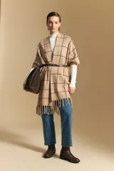 Poncho abierto de tejido de punto con diseño de cuadros grandes en contraste. Presenta un patrón reversible en tonos negro y marrón, con un estilo envolvente y versátil.