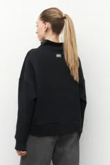 Buzo marrón de algodón con cuello alto y apliques de argollas metálicas.