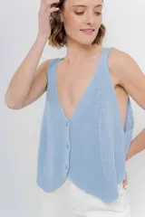 Chaleco celeste de punto con escote en V y cierre frontal con botones. Tejido calado y corte holgado.