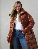 Campera puffer larga de abrigo marca BCBG Maxazria, color beige. Cuenta con capucha desmontable, cuello alto envolvente, cierre frontal bidireccional con solapa de botones a presión, bolsillos laterales, puños internos elastizados y tajos laterales con cierre en el bajo.