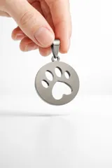 Dije circular de acero inoxidable con diseño calado de huella de mascota.