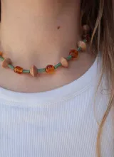 Gargantilla corta de cuentas multicolores, combinando cilindros texturizados verdes, cuentas esféricas de cristal ámbar y piezas geométricas en tono tostado.