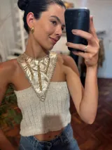 Top tejido en lurex metálico color crema, con cuello halter de cuero dorado con apliques de cuentas doradas.
