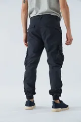 Pantalón cargo color beige, corte slim, con bolsillos laterales con botón, cierre con botón y puños en los tobillos.