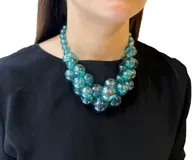 Collar de cuentas esféricas de resina translúcida color verde, con cierre de mosquetón y cadena dorada para regular el largo.