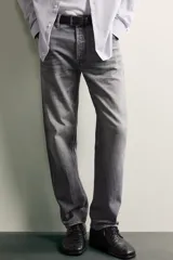 Jeans regular fit de mezclilla negra con efecto lavado, corte recto y tiro medio. Cuenta con diseño de cinco bolsillos y cierre frontal con cremallera y botón.