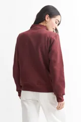 Campera verde militar de felpa liviana, con cuello alto, cierre frontal y bolsillos laterales.