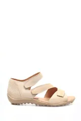 Sandalia de cuero beige con diseño de múltiples tiras con cierre de velcro. Presenta una combinación de texturas, incluyendo cuero con relieve tipo croco en el talón y la puntera, y cuero liso en las tiras superiores. Cuenta con una suela plana de goma con relieve antideslizante.