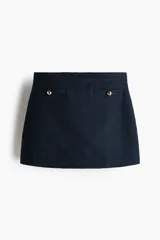 Short pollera de tiro alto en color azul marino, con bolsillos decorativos delanteros adornados con botones dorados y cierre oculto en el lateral.