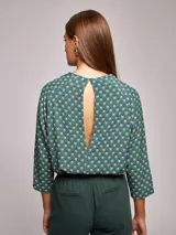 Blusa de rayón con estampado geométrico en tonos verde, amarillo, blanco y azul. Presenta un corte regular fit, cuello a la base y espalda abierta con cierre de botón en el cuello.