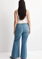 Pantalón de mezclilla de tiro medio con diseño acampanado estilo flare, trabillas para cinturón y clásico diseño de cinco bolsillos con cierre frontal de botón y cremallera.