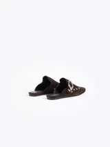 Slide de cuero descarne color marrón, con diseño de punta cerrada, detalle de tachas metálicas y hebilla decorativa en el empeine.