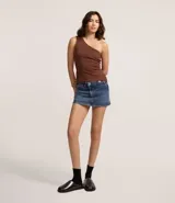 Minifalda de jeans azul oscuro, con cintura alta y cierre cruzado con botones. Presenta trabillas y bolsillos delanteros y traseros.