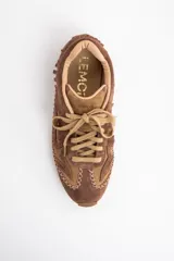 Zapatilla de perfil bajo confeccionada en gamuza combinada en tonos marrones. Presenta detalles de flecos en el lateral, costuras decorativas en forma de X a lo largo de la base y cordones al tono.