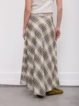Falda larga de corte cruzado con estampa a cuadros en tonos beige, verde militar y azul oscuro, con detalle de flecos en el borde delantero.