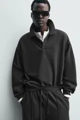 Sudadera tipo polo de corte regular, confeccionada en tejido con acabado cepillado. Presenta cuello solapa con cierre frontal de tres botones, manga larga y terminaciones en rib en puños y ruedo.