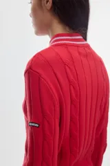 Cardigan de punto color marfil con cierre frontal completo, cuello alto y detalles de rayas en contraste en cuello, puños y ruedo. Presenta diseño de ochos verticales.