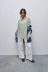 Camisa de manga larga con diseño de rayas verticales blancas y verdes, calce relajado, cuello clásico y botonadura frontal con botones perlados.