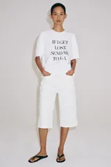 Camiseta blanca de manga corta y cuello redondo, de corte regular fit, con detalle de texto estampado en negro en el frente.