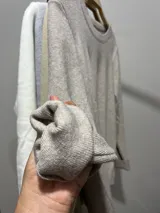 Sweater de punto fino en color crudo, con cuello redondo y mangas largas. Presenta un diseño ajustado y minimalista, ideal para usar como prenda base o sola.