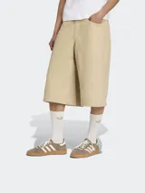 Bermuda color beige de corte ancho con tres líneas verticales a los costados y logo de la marca bordado en la pierna izquierda.