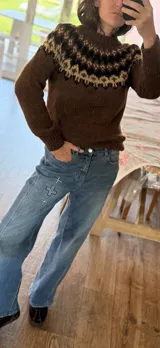Sweater tejido a mano con diseño de canesú estampado en tonos marrón, crema y verde sobre base color tostado. Presenta cuello redondo, puños y ruedo acanalados.