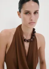 Top de poliéster color marrón con cuello halter y escote drapeado, sin mangas y diseño recto.