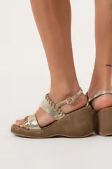 Sandalias de cuero color dorado con plataforma y taco de cuña forrado en gamuza marrón.