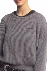 Buzo de punto inglés grueso en color gris melange, de corte amplio con hombros caídos y mangas largas, con sutil bordado de la marca en el pecho.