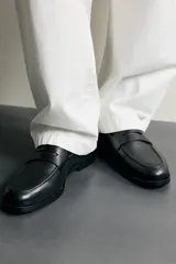 Mocasín de vestir para hombre, confeccionado en cuero marrón con diseño clásico de antifaz en el empeine, horma redonda y suela con ligero tacón.