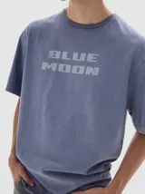 Remera de algodón con efecto lavado, cuello redondo y mangas cortas. Presenta una estampa frontal con el texto 'BLUE MOON'.