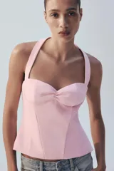 Top negro con estampado de lunares blancos, escote halter y diseño estructurado tipo corset con copas fruncidas en el centro.