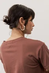 Remera marrón con mangas cortas y cuello redondo, confeccionada en algodón, con detalle de logo bordado en la parte posterior del cuello.