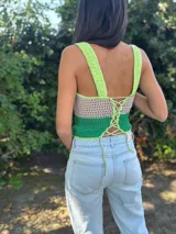 Top corto tejido de punto a crochet, sin mangas, con diseño multicolor en celeste, beige y azul, y aberturas frontales estratégicas tipo cut-out.