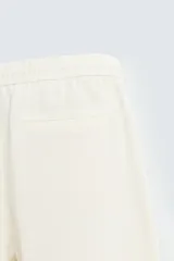 Pantalón de calce relajado confeccionado en tejido de viscosa y yute color tostado. Presenta cintura elástica ajustable con cordón, bolsillos laterales, bolsillos traseros de vivo y cierre frontal con cremallera y botón.