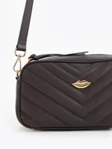 Bandolera marrón oscura de cuero vacuno con diseño matelasseado en chevron. Cuenta con una correa larga regulable, herrajes metálicos dorados y un aplique dorado en forma de labios en el frente.