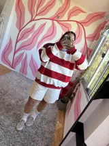 Buzo deportivo a rayas horizontales rojas y crudas, con cuello redondo celeste y logo bordado en el pecho.