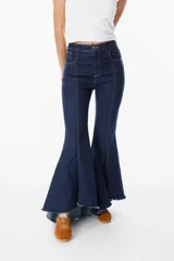 Jean elastizado azul oscuro con diseño de volados en la parte baja de la pierna, ruedo descosido con juego de largos (más largo atrás que adelante).