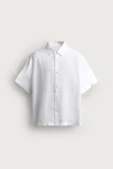 Camisa regular fit confeccionada en tejido de lino, color blanco, con cuello solapa, manga corta y cierre frontal de botonadura.