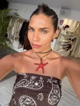 Collar con dije de estrella de mar grande de color rojo vibrante, suspendido de un tiento negro fino.