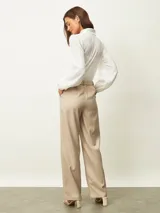 Pantalón de vestir beige de corte recto y tiro alto, con pinzas frontales y trabillas para cinturón.
