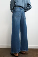 Jeans de tiro alto con diseño de pierna ancha y cinco bolsillos. Cuenta con cierre frontal mediante cremallera y botón metálico.