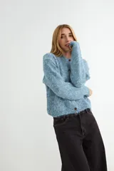 Cardigan de tejido de punto jaspeado en tonos rosados y violetas, con cuello redondo y cierre frontal de botones marrones.