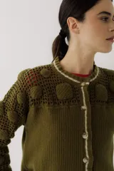 Saco de punto color beige, con diseño de calados en la parte superior y mangas, cierre frontal con botones y cuello redondo.