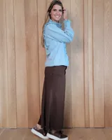 Pollera larga de corte recto en denim color arena, con diseño de cinco bolsillos, cierre frontal con botón y costuras a la vista.