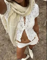 Conjunto de dos piezas tejido en crochet color blanco, compuesto por una camisa de manga corta con cierre frontal de botones y un short de tiro alto.