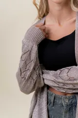 Cardigan tejido liviano color beige con efecto brillante y calados en las mangas. Diseño abierto y corte relajado.