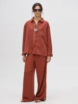 Pantalón de vestir color ladrillo, de corte holgado y tiro alto, con caída recta y detalle de diseño al costado.